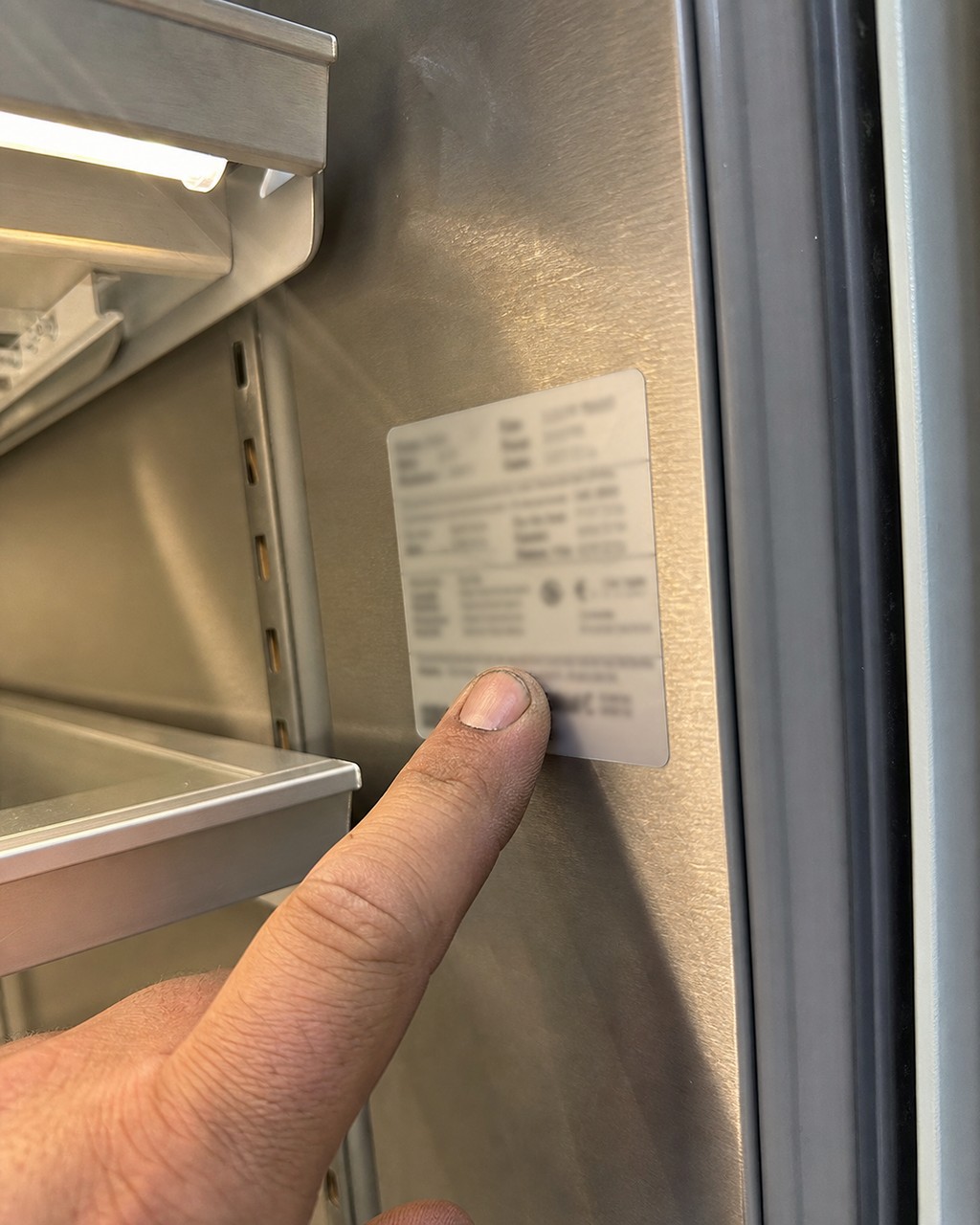 Reading a Sub-Zero model and serial number tag inside a built-in refrigerator in Walnut Creek